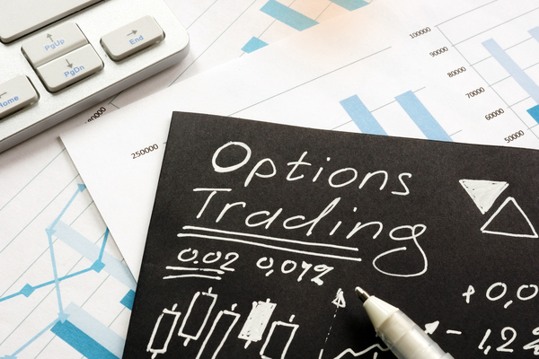 Person writing on black paper with white ink options trading information.