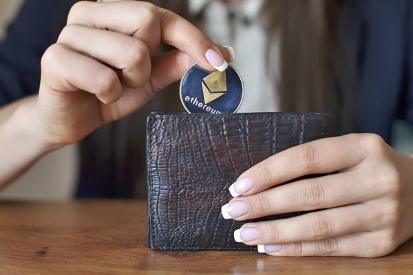 Placing a gold coin with ethereum logo into a wallet.