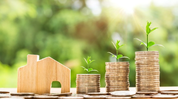 Stack of coins and a small wooden replica of a house.