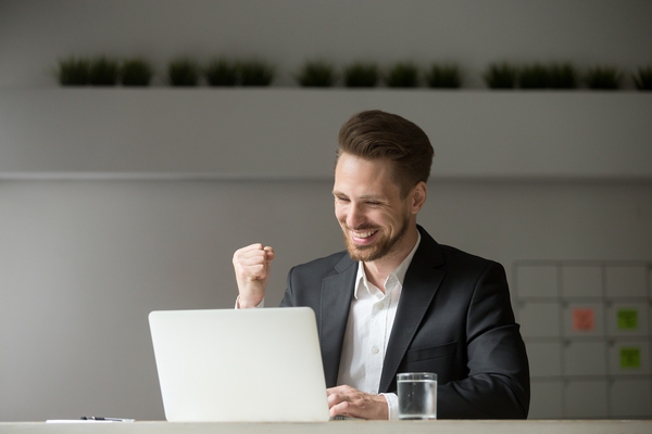 Man in front of a laptop computer smiling.