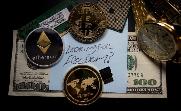 US 100 dollar bill surrounded by cryptocurrency gold and silver coins.