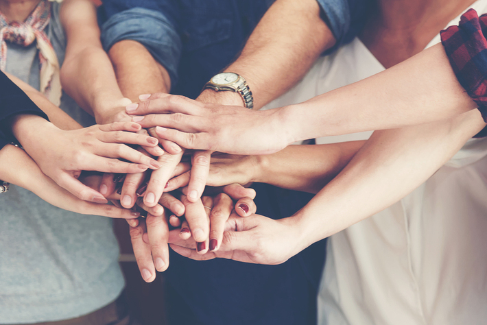 People joining hands in the center of a circle.