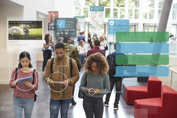 Group of people walking through a large open hallway using tablets or mobile phones.