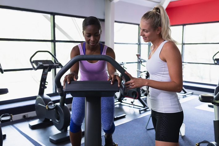 Woman on a stationary bicycle consulting with a fitness expert.