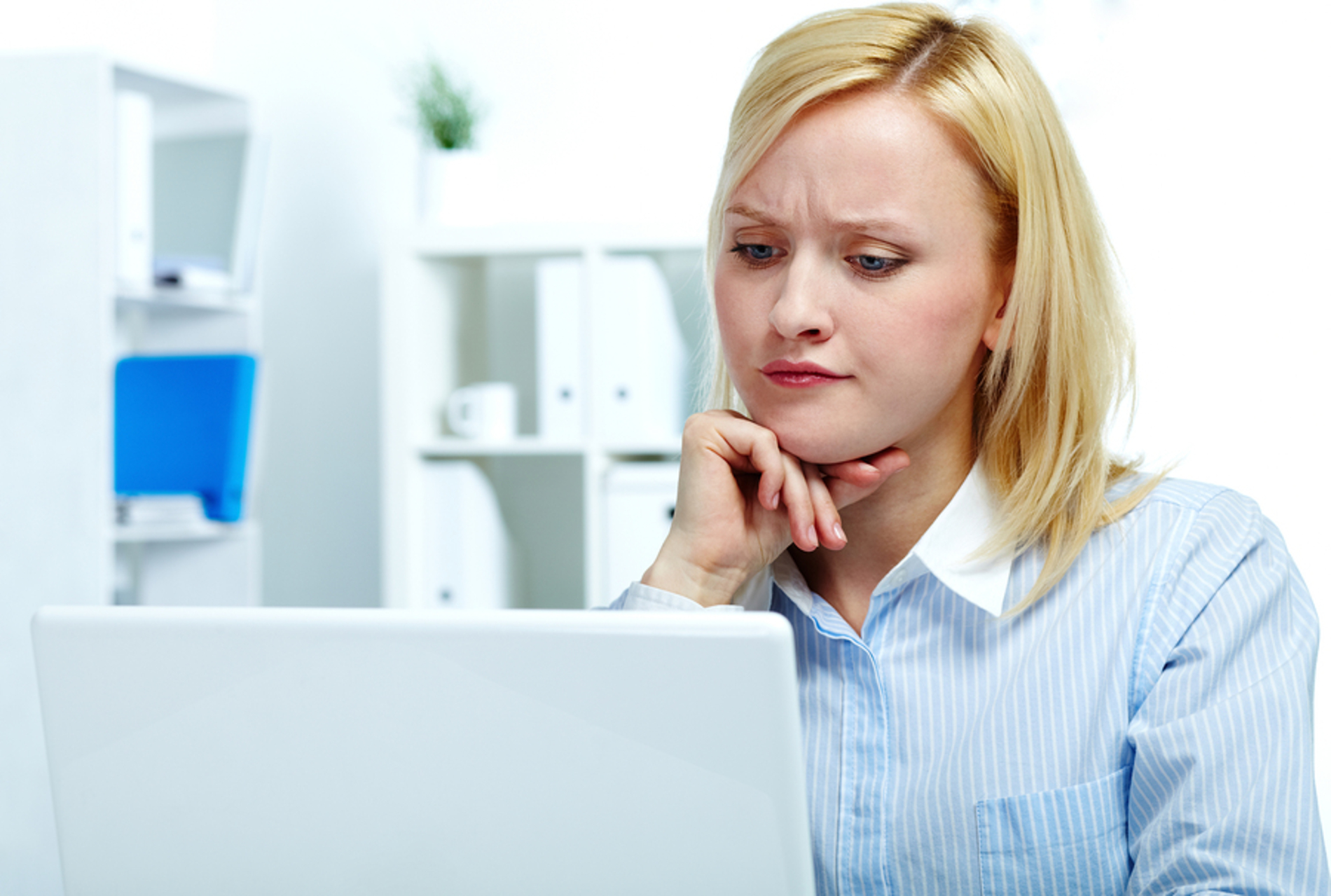 Woman looking worried while staring at her computer screen. Woman looking worried while staring at her computer screen.