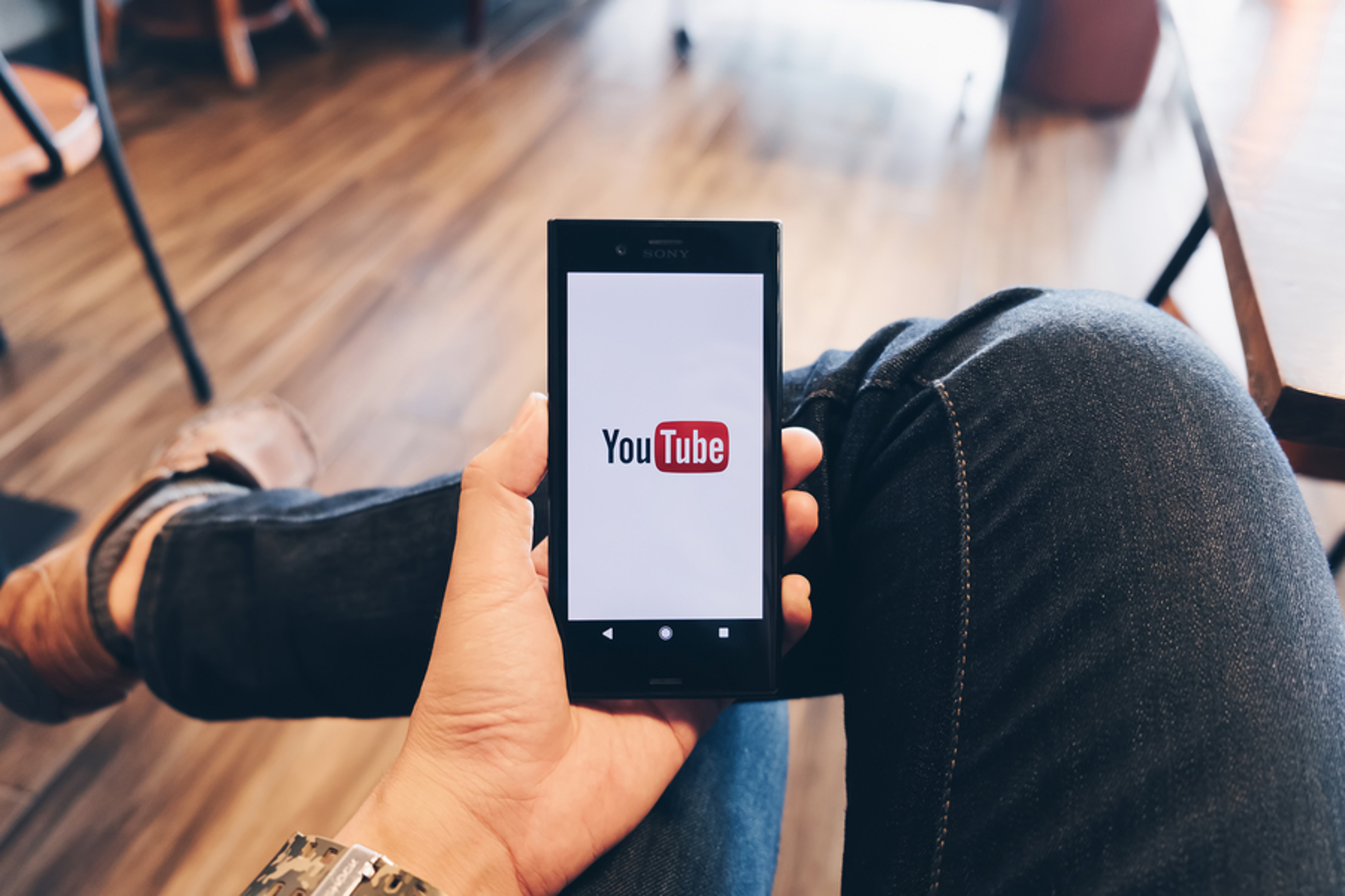 Person looking at the YouTube app on their phone. Person looking at the YouTube app on their phone.