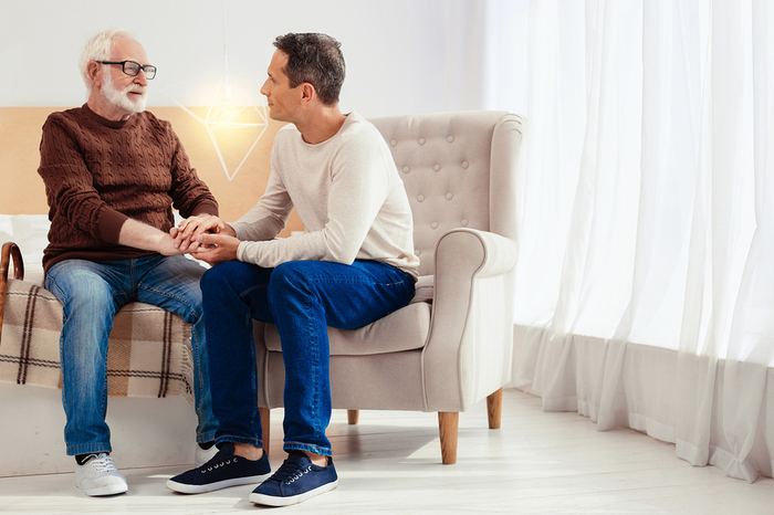 Older gentleman sitting with a caregiver.