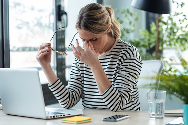Woman appearing stressed at her desk.