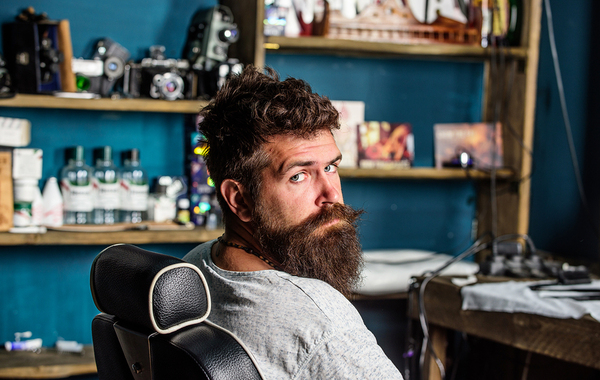 Man with a beard sitting in a chair.