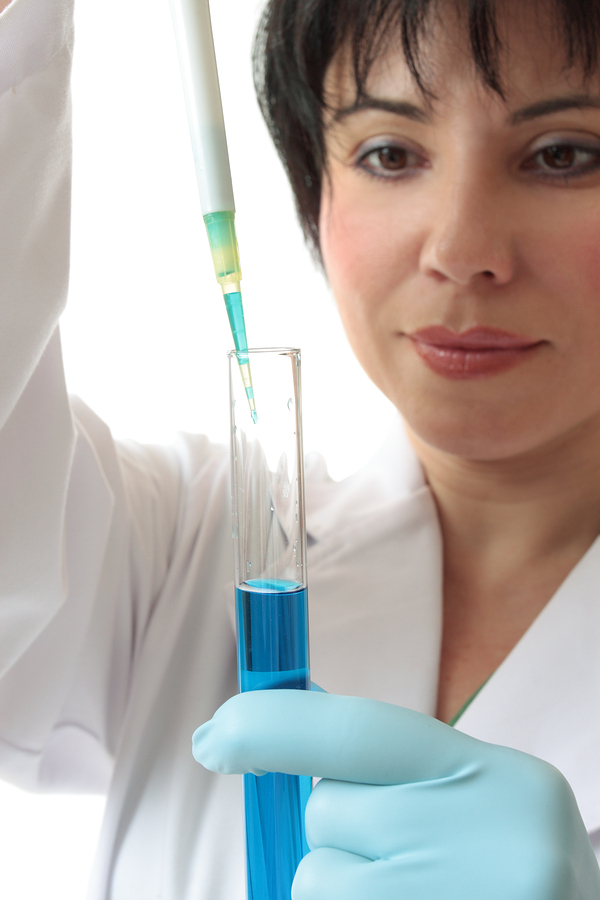 Woman placing liquid in a glass tube.