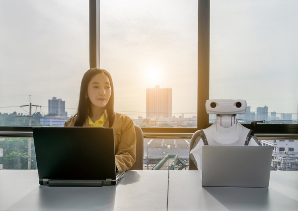 Woman sitting next to a robot.