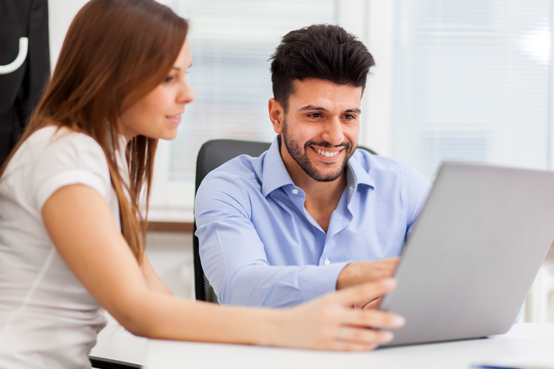 Two colleagues looking at a laptop screen together.