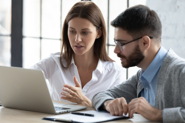 Two colleagues looking at data on a laptop.