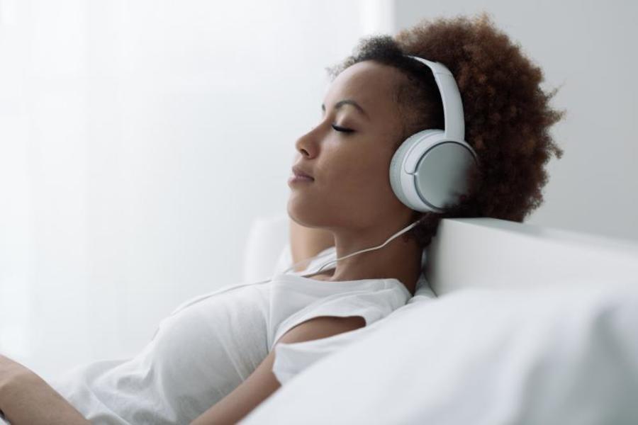 Woman laying down with headphones on.