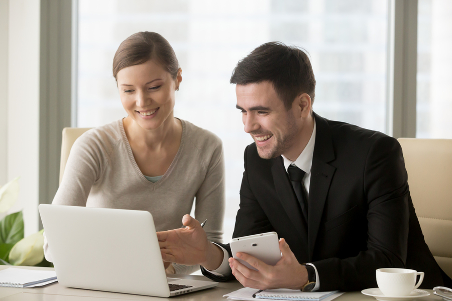 Two coworkers discussing a project in front of a laptop computer.