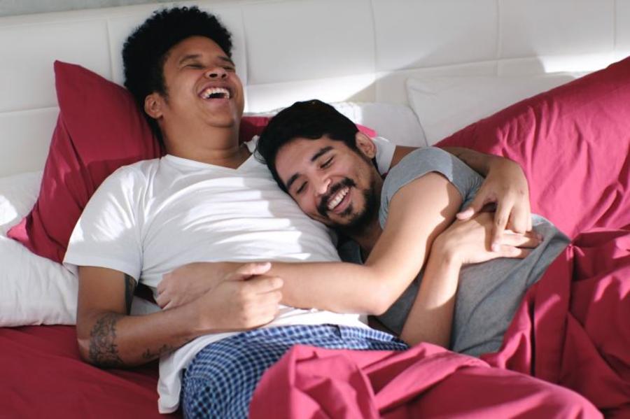 Two men lying in bed together.