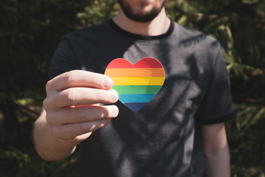 Person holding a rainbow colored heart.