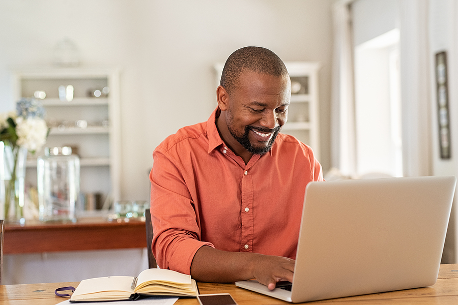 Smiling man typing on a laptop keyboard.