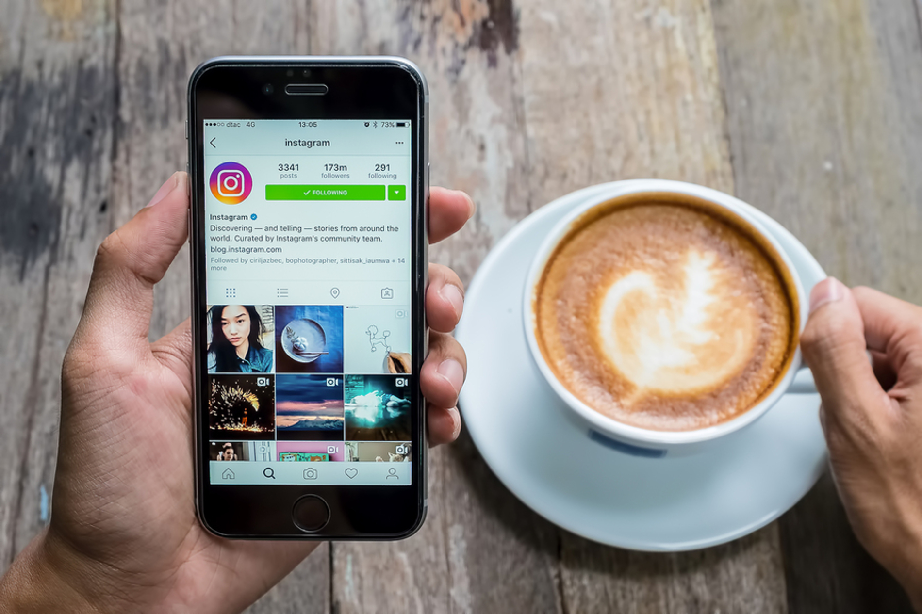 Person looking at the Instagram app on their phone while drinking coffee. Person looking at the Instagram app on their phone while drinking coffee.