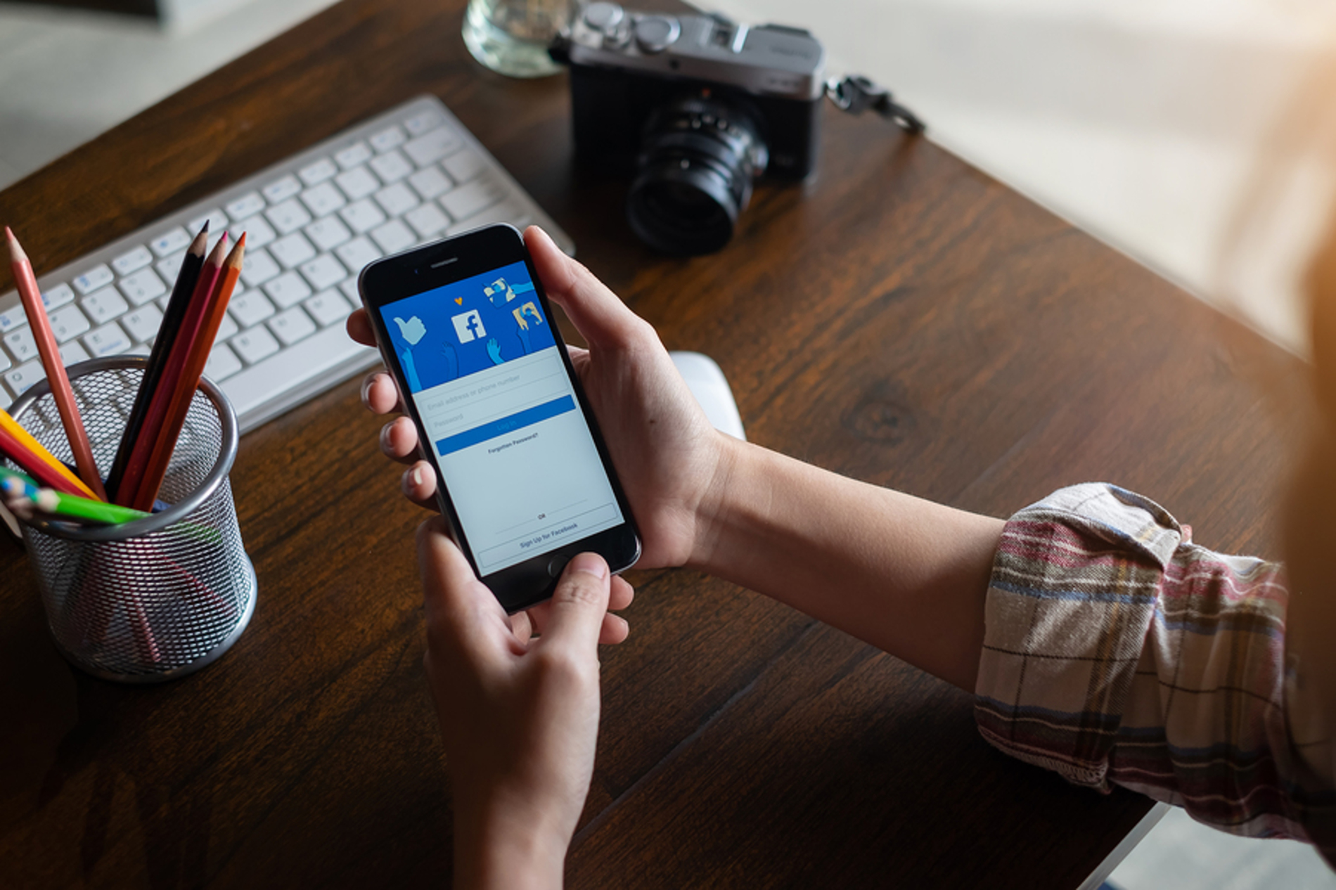 Person looking at the Facebook app on their phone. Person looking at the Facebook app on their phone.