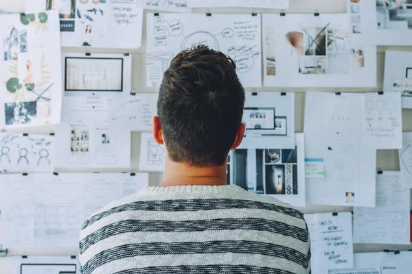 Man studying documents pinned to a wall.