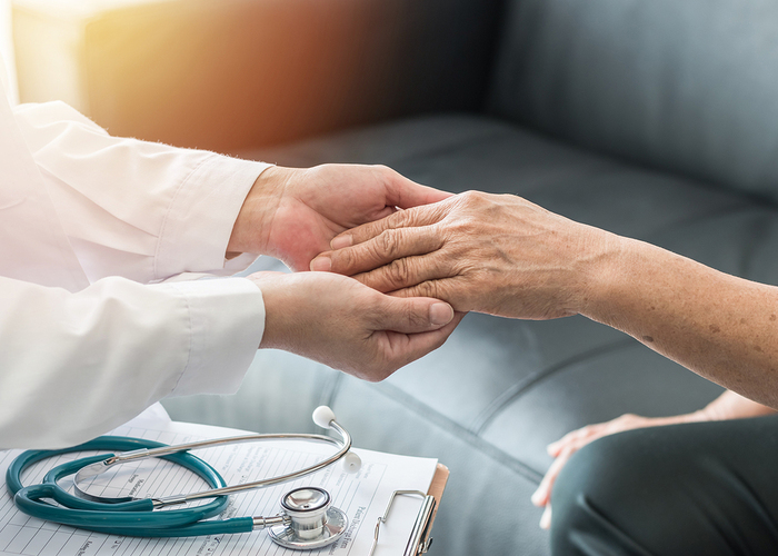 Medical doctor holding a patient's hand.