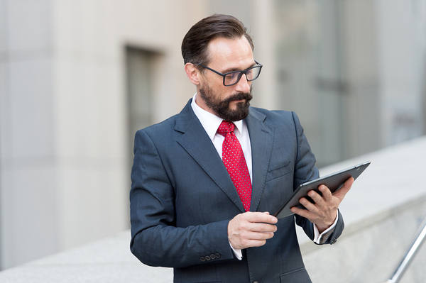 Man in a business suit looking at a tablet.