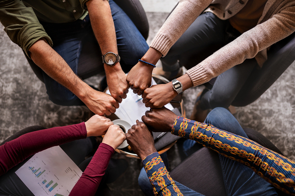 Group of people touching fists together in a circle.