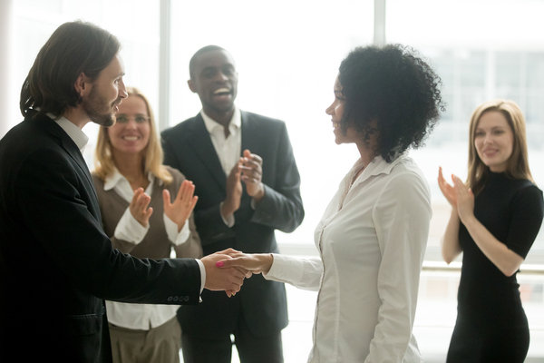 Group of colleagues standing around clapping.