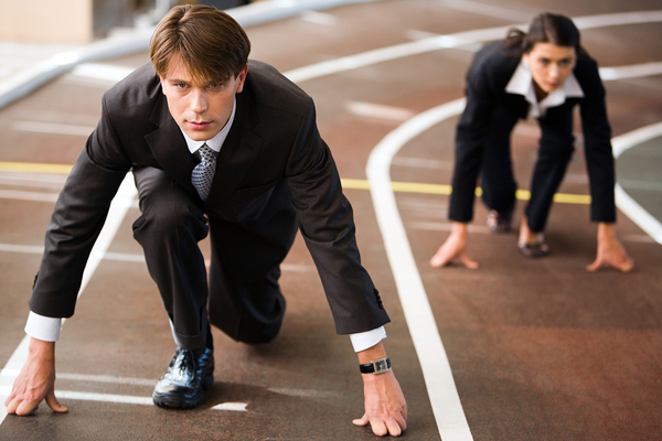 Two people in business suits on a running track getting ready to start.