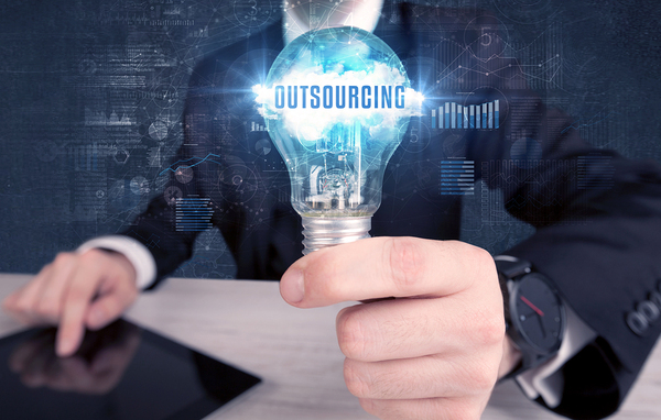 Person holding a lightbulb labeled outsourcing.