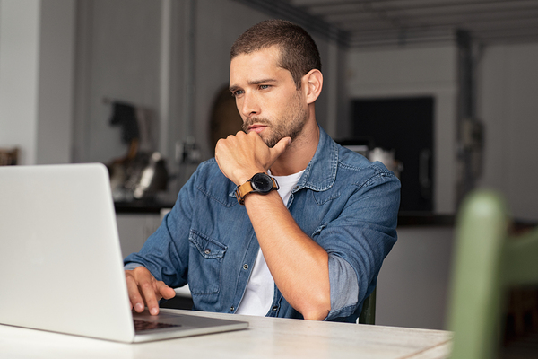 Man looking intently at his laptop computer screen.