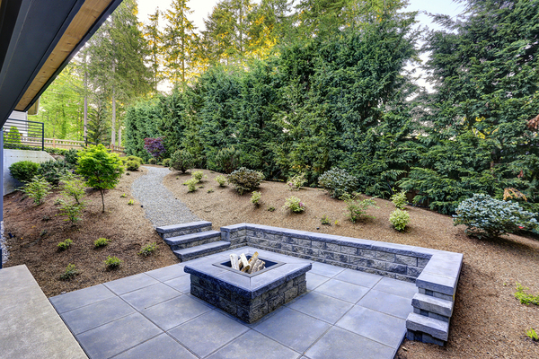 Beautiful patio with stone wall and fire pit in the center.