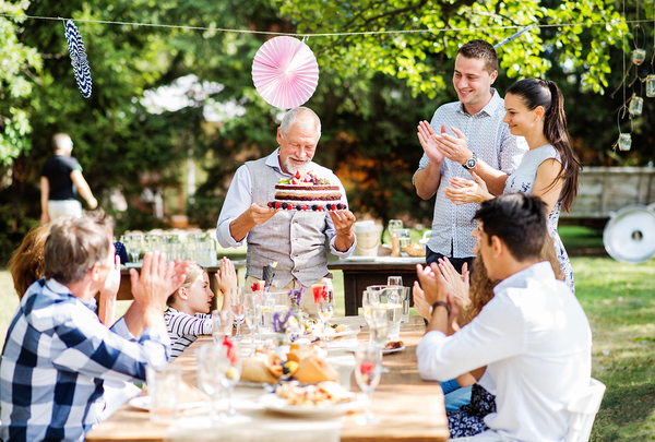 Family sitting around a table outside clapping and smiling.
