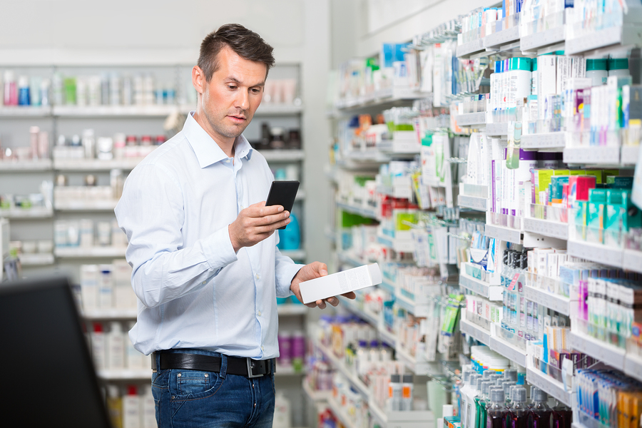 Man shopping for medication while referring to his phone.