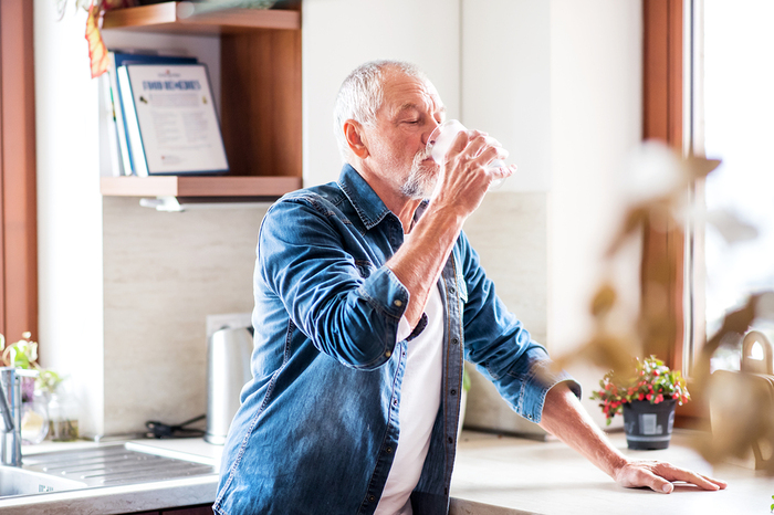 Older man drinking a glass of water.