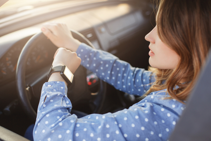 Woman looking at her watch while driving a car.