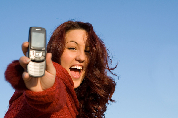 Woman holding out a phone smiling.