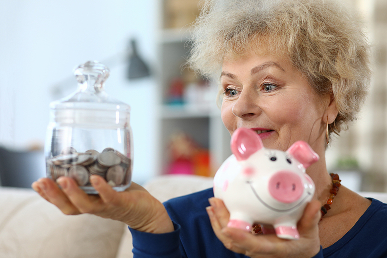 Woman holing a glass jar filled with coins.