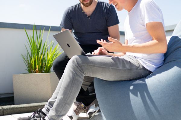 Two colleagues looking at a laptop screen and having a discussion