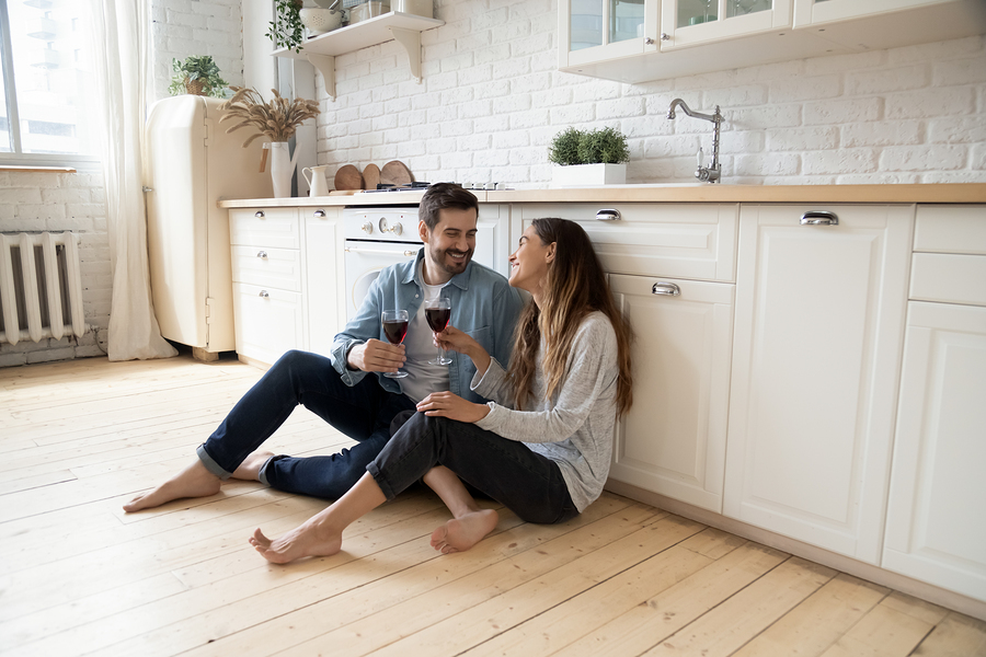 Smiling couple sitting on the floor drinking wine.