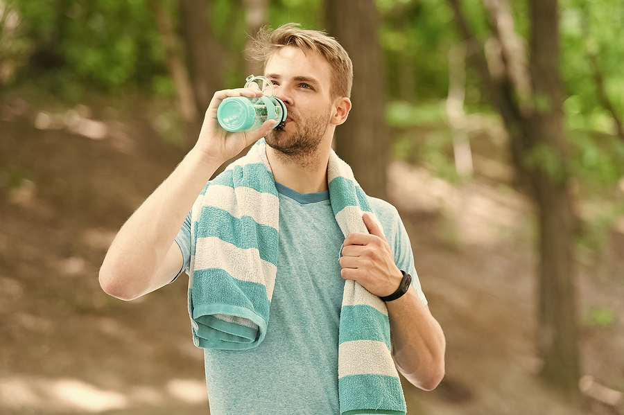 Man drinking from a water bottle outside.