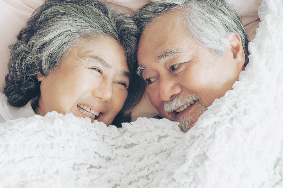 Couple smiling at each other in bed.