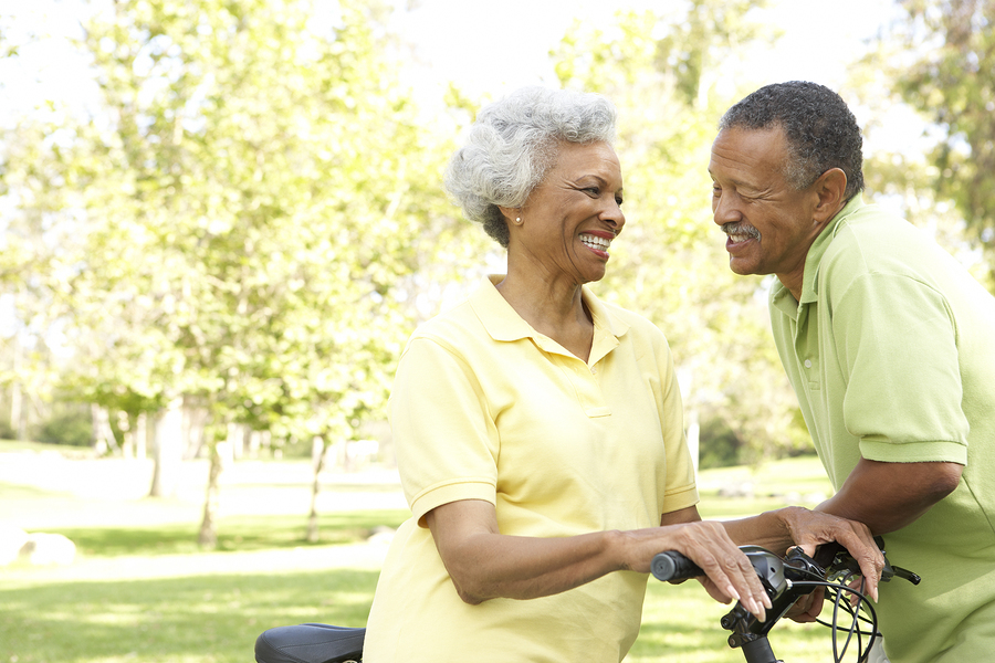 Couple smiling at each other while holding onto bicycles.