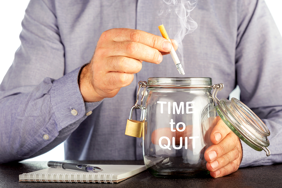 Man putting a cigarette into a jar labeled time to quit.