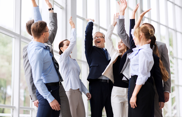 Group of colleagues raising up their arms in triumph.