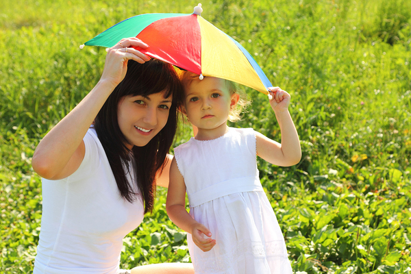 Woman and child sharing a small kid-sized umbrella.