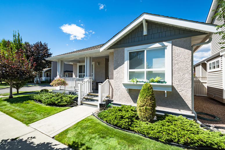 Stone front house with a small green front yard and shrubbery.