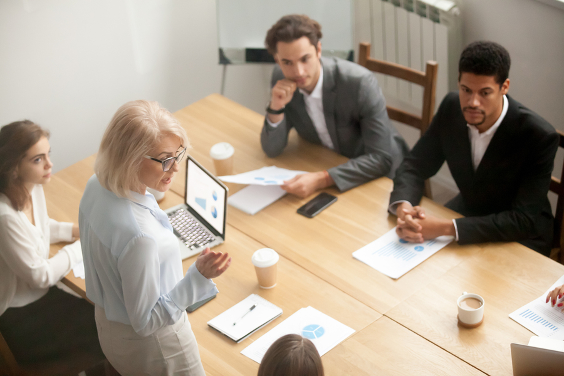 Person presenting to coworkers around a conference table.