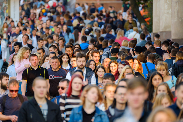 Crowd of people walking down a sidewalk.